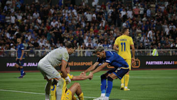 Radu Dragusin being held up by his goalkeeper and a Kosovo player during Romania's nations league opener 