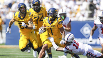Aug 30, 2025; Morgantown, West Virginia, USA; West Virginia Mountaineers running back Jahiem White (1) runs the ball and is tackled by Robert Morris Colonials quarterback Jake Wolfe (12) during the first quarter at Milan Puskar Stadium. Mandatory Credit: Ben Queen-Imagn Images