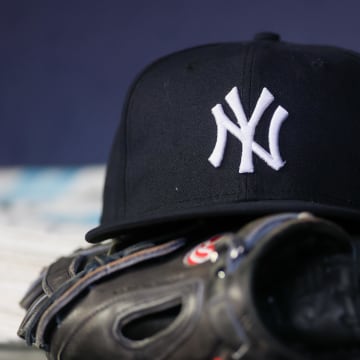 A detailed view of a New York Yankees hat and glove on the bench against the Atlanta Braves in the third inning at Truist Park. 