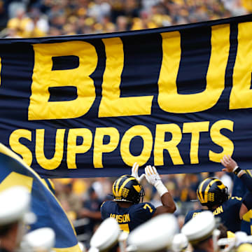 Sep 28, 2019; Ann Arbor, MI, USA; Michigan Wolverines linebacker Khaleke Hudson (7) and quarterback Shea Patterson (2) jump and touch the banner before the game against the Rutgers Scarlet Knights at Michigan Stadium. Mandatory Credit: Raj Mehta-Imagn Images