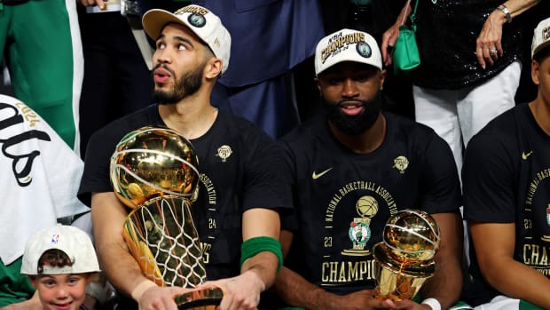 Jayson Tatum holds the Larry O’Brien Trophy while sitting next to Jaylen Brown, who has the 2024 NBA Finals MVP Award.