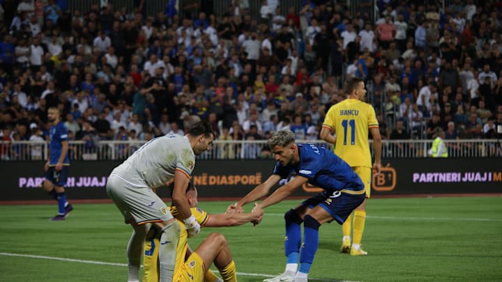 Radu Dragusin being held up by his goalkeeper and a Kosovo player during Romania's nations league opener 