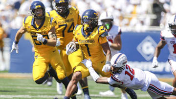 Aug 30, 2025; Morgantown, West Virginia, USA; West Virginia Mountaineers running back Jahiem White (1) runs the ball and is tackled by Robert Morris Colonials quarterback Jake Wolfe (12) during the first quarter at Milan Puskar Stadium. Mandatory Credit: Ben Queen-Imagn Images