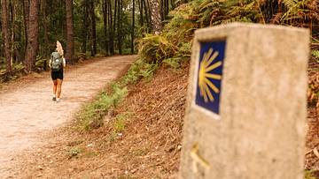 Camino de Santiago sign with pilgrim in background.