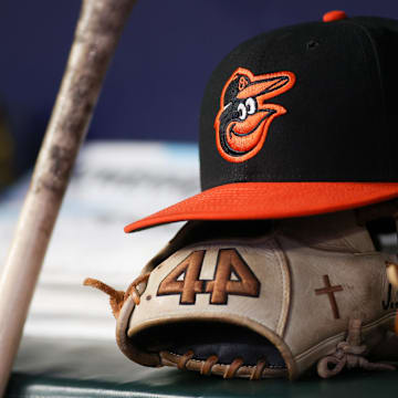 May 5, 2023; Atlanta, Georgia, USA; A detailed view of a Baltimore Orioles hat and glove in the dugout during a game against the Atlanta Braves in the seventh inning at Truist Park. Mandatory Credit: Brett Davis-Imagn Images
