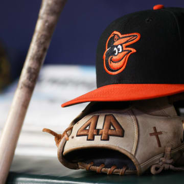 A detailed view of a Baltimore Orioles hat and glove in the dugout