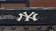 Aug 17, 2020; Bronx, New York, USA; A general view of rain falling on the  New York Yankees logo on the first base dugout roof during a rain delay in the game between the New York Yankees and the Boston Red Sox. Mandatory Credit: Vincent Carchietta-Imagn Images
