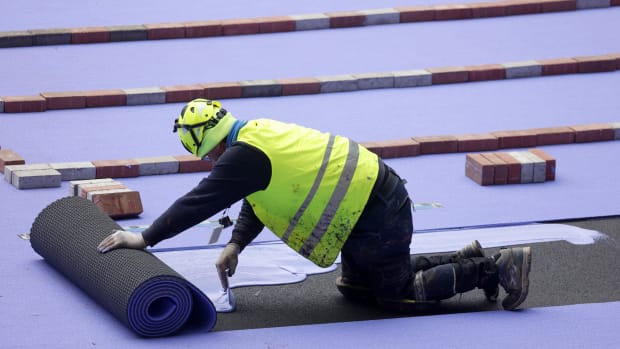 A worker laying down the purple track at the Stade de France.