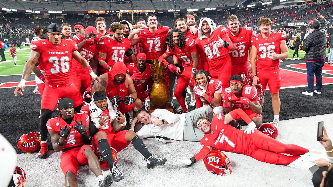 Nov 21, 2025; Paradise, Nevada, USA; UNLV Rebels head coach Dan Mullen and his players pose with the Golden Pineapple trophy after the Rebels defeated the Hawaii Rainbow Warriors 38-10 at Allegiant Stadium. Mandatory Credit: Stephen R. Sylvanie-Imagn Images Nov 21, 2025; Paradise, Nevada, USA; UNLV Rebels head coach Dan Mullen and his players pose with the Golden Pineapple trophy after the Rebels defeated the Hawaii Rainbow Warriors 38-10 at Allegiant Stadium. Mandatory Credit: Stephen R. Sylvanie-Imagn Images