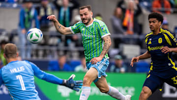 Apr 19, 2025; Seattle, Washington, USA;  Seattle Sounders forward Jordan Morris (13) takes a shot against Nashville SC goalkeeper Joe Willis (1) and defender Chris Applewhite (33) during the second half at Lumen Field. Mandatory Credit: Stephen Brashear-Imagn Images