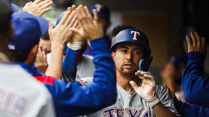 Aug 2, 2025; Seattle, Washington, USA; Texas Rangers catcher Kyle Higashioka (11) high-fives teammates in the dugout after hitting a two-run home run against the Seattle Mariners during the third inning at T-Mobile Park. 