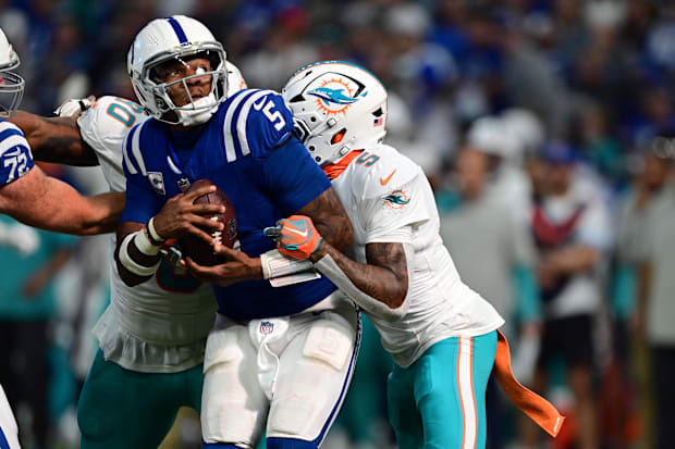 Indianapolis Colts quarterback Anthony Richardson is pressured by a Dolphins defender in a blue jersey.