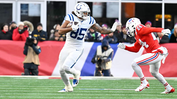 Colts tight end Drew Ogletree (all-white uniform) tries to stiff arm a defender.