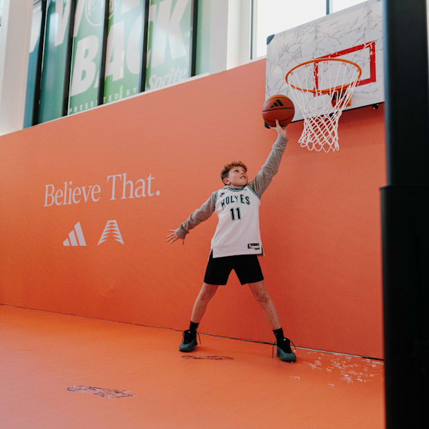 A kid dunks a basketball at an adidas experience.