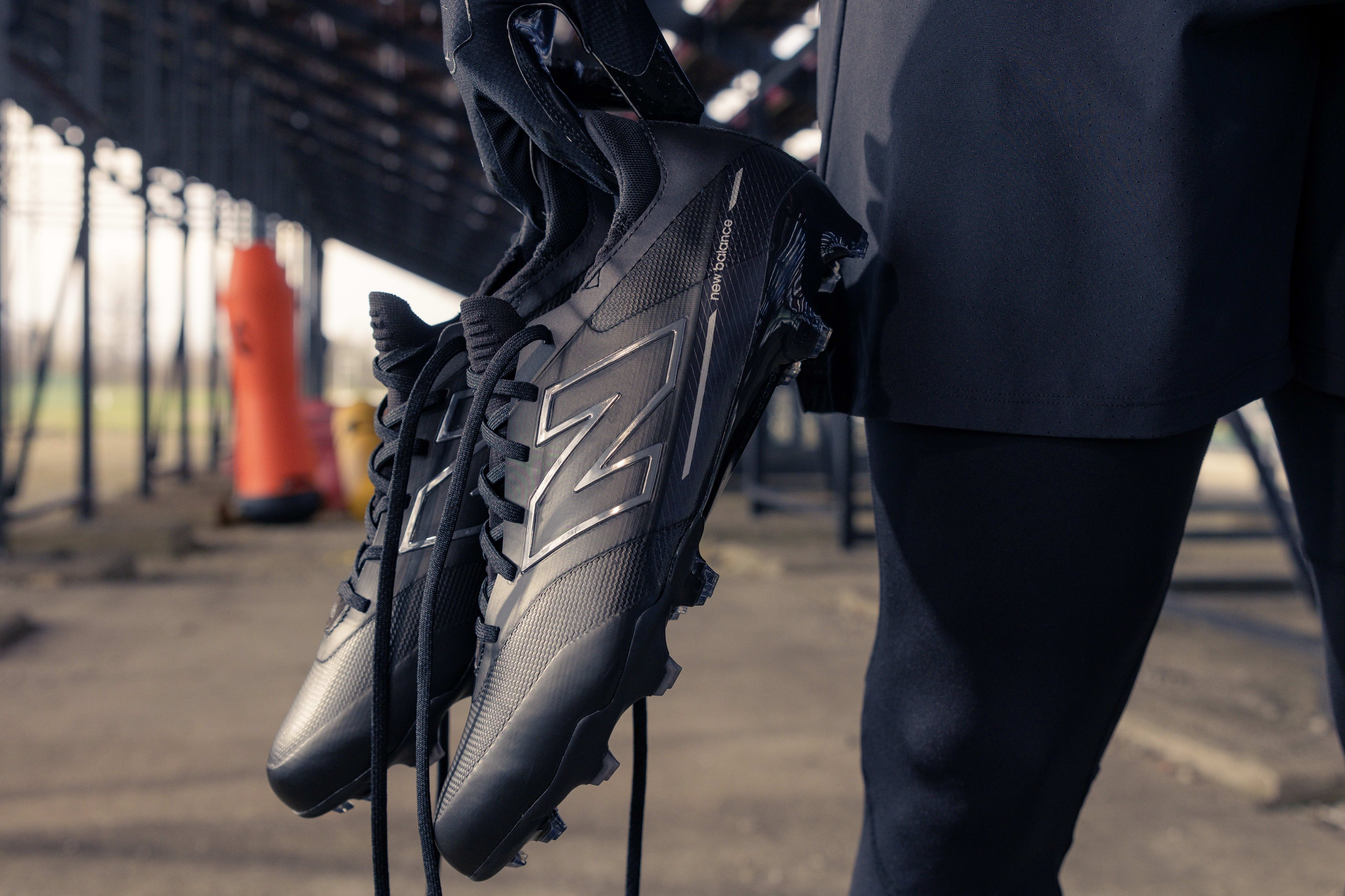 Side view of black New Balance football cleats.