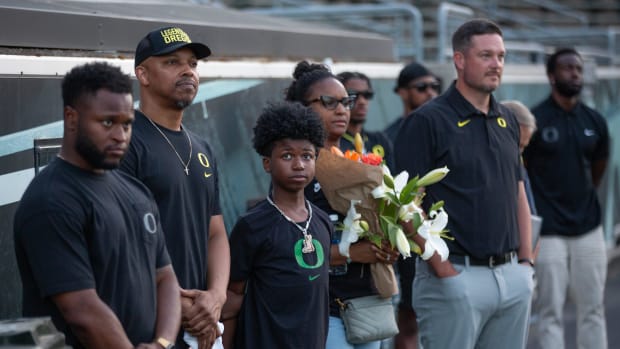 Raymond and Ebbony Jackson and son are joined by Oregon staff Osman Kamara, left, and Oregon coach Dan Lanning during a vigil