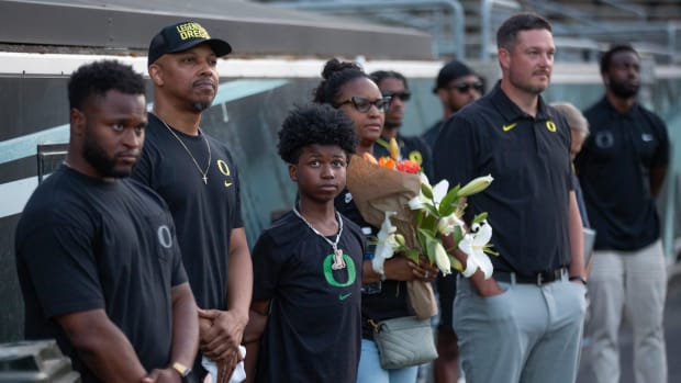 Raymond and Ebbony Jackson and son are joined by Oregon staff Osman Kamara, left, and Oregon coach Dan Lanning during a vigil