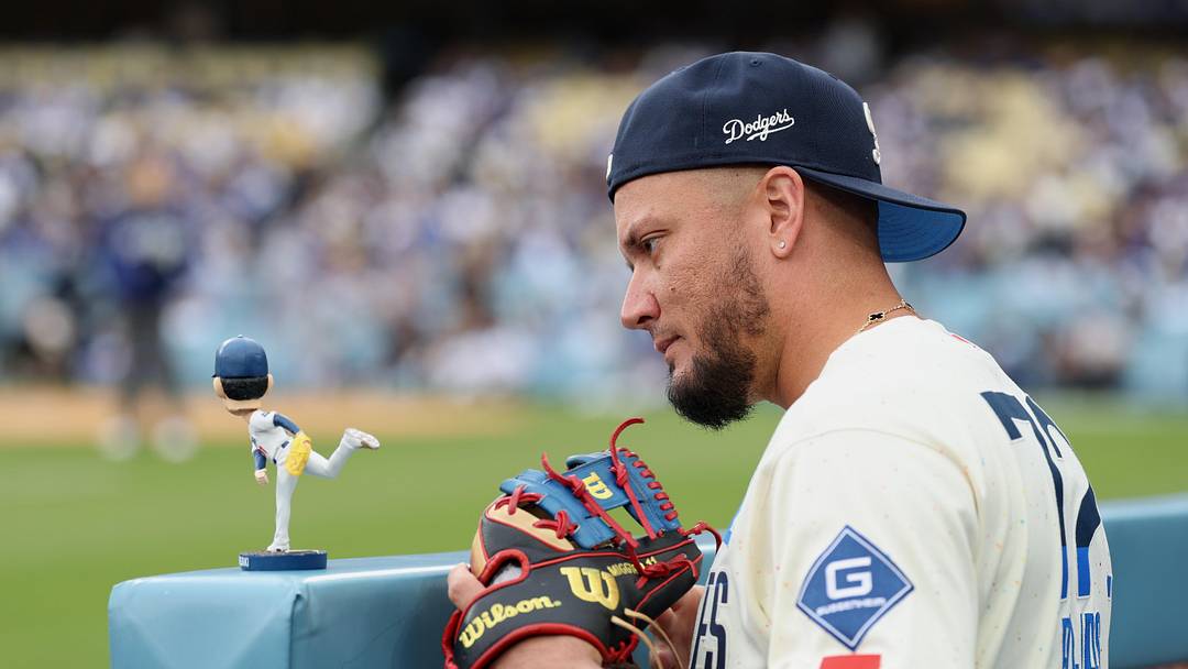 Apr 25, 2026; Los Angeles, California, USA; Los Angeles Dodgers infielder Miguel Rojas (72) looks at a bobblehead depicting pitcher Roki Sasaki (not pictured) before the game against the Chicago Cubs at Dodger Stadium. Mandatory Credit: Kiyoshi Mio-Imagn Images