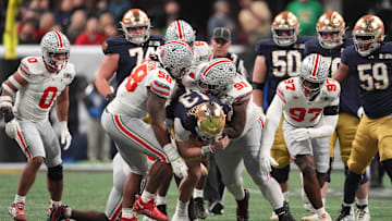 Jan 20, 2025; Atlanta, GA, USA; Notre Dame Fighting Irish quarterback Riley Leonard (13) is tackled by Ohio State Buckeyes defensive tackle Ty Hamilton (58) and Ohio State Buckeyes defensive tackle Tyleik Williams (91) in the CFP National Championship college football game at Mercedes-Benz Stadium. Mandatory Credit: Dale Zanine-Imagn Images