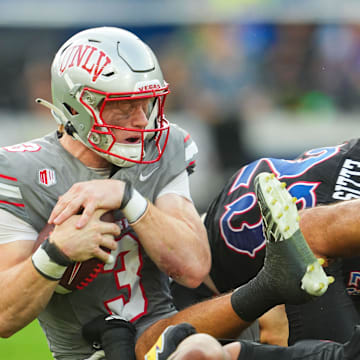 Sep 13, 2024; Kansas City, Kansas, USA; UNLV Rebels quarterback Matthew Sluka (3) is tackled by several Kansas Jayhawks during the first half at Children's Mercy Park. Mandatory Credit: Jay Biggerstaff-Imagn Images