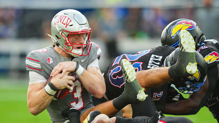 Sep 13, 2024; Kansas City, Kansas, USA; UNLV Rebels quarterback Matthew Sluka (3) is tackled by several Kansas Jayhawks during the first half at Children's Mercy Park. Mandatory Credit: Jay Biggerstaff-Imagn Images