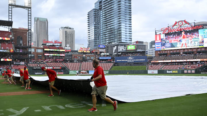 Jul 13, 2025; St. Louis, Missouri, USA;  St. Louis Cardinals grounds crew pulls the tarp on the field during a rain delay in the third inning of a game between the St. Louis Cardinals and the Atlanta Braves at Busch Stadium. Mandatory Credit: Jeff Curry-Imagn Images