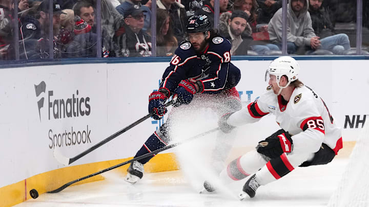 Blue Jackets forward Kirill Marchenko shields the puck from Senators defenseman Jake Sanderson. 