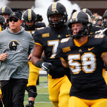 Sep 17, 2022; Boone, North Carolina, USA;  Appalachian State Mountaineers head coach Shawn Clark (middle) runs on the field before the game against the Troy Trojans at Kidd Brewer Stadium. Mandatory Credit: Reinhold Matay-USA TODAY Sports