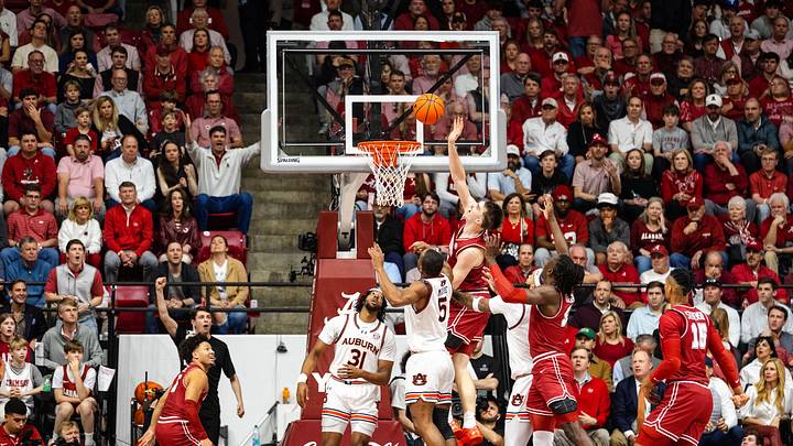 Feb 15, 2025; Tuscaloosa, Alabama, USA; Alabama Crimson Tide forward Grant Nelson (4) shoots against Auburn Tigers forward Chris Moore (5) and forward Chaney Johnson (31) during the first half at Coleman Coliseum. Mandatory Credit: Will McLelland-Imagn Images