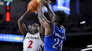 Jan 11, 2025; Cincinnati, Ohio, USA;  Cincinnati Bearcats guard Jizzle James (2) drives to the basket against Kansas Jayhawks forward KJ Adams Jr. (24) in the first half at Fifth Third Arena. Mandatory Credit: Aaron Doster-Imagn Images