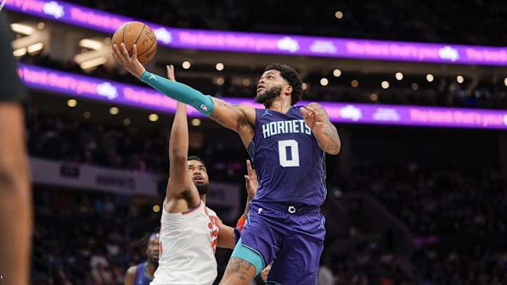 Mar 20, 2025; Charlotte, North Carolina, USA; Charlotte Hornets forward Miles Bridges (0) drives to the basket against New York Knicks center Karl-Anthony Towns (32) during the second half at Spectrum Center. Mandatory Credit: Jim Dedmon-Imagn Images