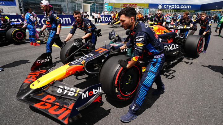 May 4, 2024; Miami Gardens, Florida, USA; Crewmembers push the car of Red Bull Racing driver Sergio Perez (11) on the grid before the F1 Sprint Race at Miami International Autodrome. Mandatory Credit: John David Mercer-USA TODAY Sports