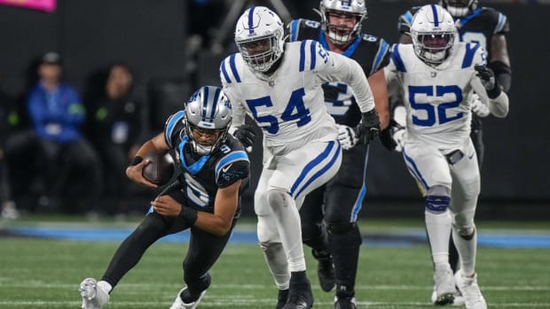 Colts defender Dayo Odeyingbo (all-white uniform) runs down Panther QB Bryce Young (all-black uniform) for a tackle. 