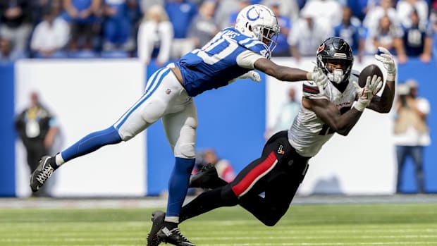 Texans receiver Nico Collins (white jersey; blue pants) makes a diving catch around the sideline. 