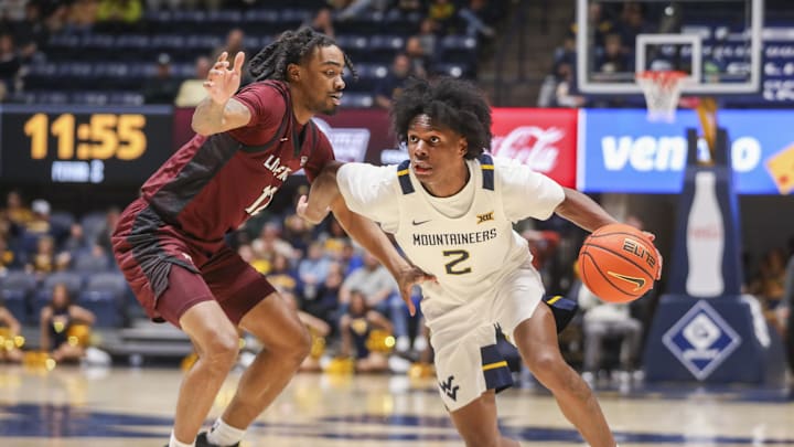 Dec 9, 2025; Morgantown, West Virginia, USA; West Virginia Mountaineers guard Amir Jenkins (2) dribbles past Little Rock Trojans guard Tracy Steele Jr. (12) during the second half at Hope Coliseum. Mandatory Credit: Ben Queen-Imagn Images
