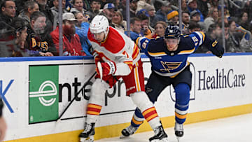 Jan 14, 2025; St. Louis, Missouri, USA; Calgary Flames defenseman Kevin Bahl (7) and St. Louis Blues center Radek Faksa (12) battle for the puck in the second period at Enterprise Center. Mandatory Credit: Joe Puetz-Imagn Images