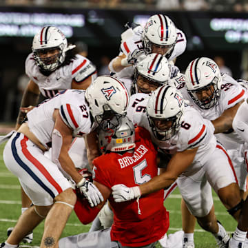 Aug 31, 2024; Tucson, Arizona, USA; Arizona Wildcats defensive back Owen Goss (27), Arizona Wildcats linebacker Taye Brown (6), Arizona Wildcats defensive back (13) and Arizona Wildcats defensive lineman Cyrus Durham (99) all tackle New Mexico Lobos tight end Trace Bruckler (5) on final play at the end of the fourth quarter at Arizona Stadium. 