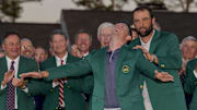 Scheffler places the green jacket on 2025 Masters champion Rory McIlroy.