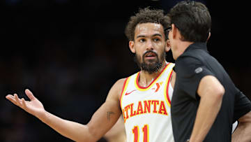 Trae Young #11 of the Atlanta Hawks speaks with head coach Quin Snyder.