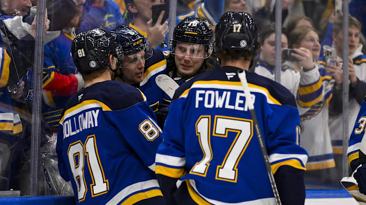 Mar 20, 2025; St. Louis, Missouri, USA;  St. Louis Blues defenseman Philip Broberg (6) is congratulated by center Dylan Holloway (81) center Oskar Sundqvist (70) and defenseman Cam Fowler (17) after scoring the game winning goal against the Vancouver Canucks in overtime at Enterprise Center. Mandatory Credit: Jeff Curry-Imagn Images