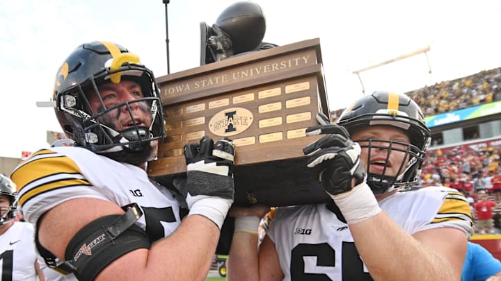 Sep 9, 2023; Ames, Iowa, USA; Iowa Hawkeyes offensive lineman Nick DeJong (56) and offensive lineman Logan Jones (65) carry the Cy-Hawk trophy after the game against the Iowa State Cyclones at Jack Trice Stadium. Mandatory Credit: Jeffrey Becker-Imagn Images