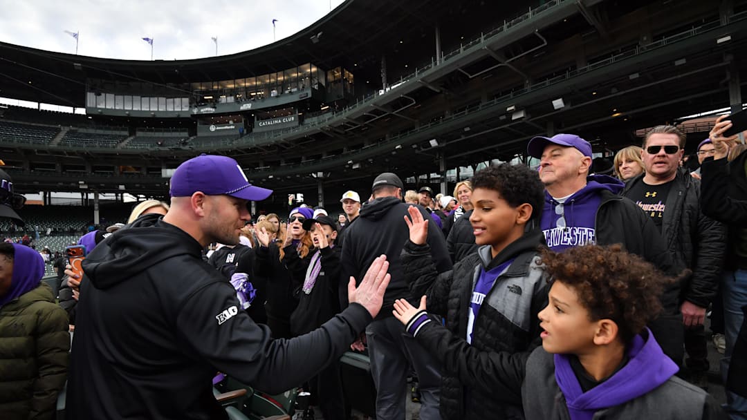 Northwestern Wildcats head coach David Braun celebrates with young fans after his team’s victory against the Minnesota Golden Gophers at Wrigley Field. 
