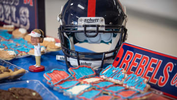 Ole Miss Themed material including a helmet, baked cookies, and a bobblehead Lane Kiffin figure sits on a table during the Cam Clark Ole Miss signing in Medina, Tenn., on Wednesday, Dec. 20, 2023.