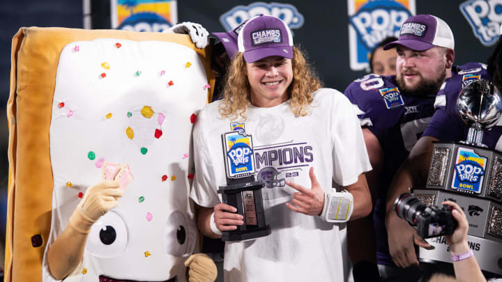 Dec 28, 2023; Orlando, FL, USA; Kansas State quarterback Avery Johnson (2) celebrates his MPV honors with the pop-tart mascot at Camping World Stadium. Mandatory Credit: Jeremy Reper-USA TODAY Sports