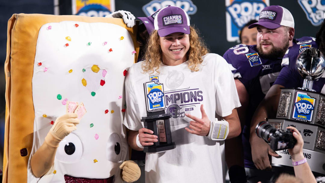 Dec 28, 2023; Orlando, FL, USA; Kansas State quarterback Avery Johnson (2) celebrates his MPV honors with the pop-tart mascot at Camping World Stadium. Mandatory Credit: Jeremy Reper-USA TODAY Sports