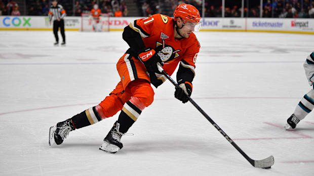 Hockey player in orange uniform skates with the puc