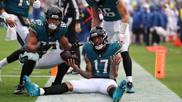 Dec 7, 2025; Jacksonville, Florida, USA;  Jacksonville Jaguars wide receiver Tim Patrick (17) sits on the field after catching a touchdown pass, as teammates tight end Brenton Strange (85) and quarterback Trevor Lawrence (16) join in against the Indianapolis Colts during the first half at EverBank Stadium. Mandatory Credit: Matt Pendleton-Imagn Images