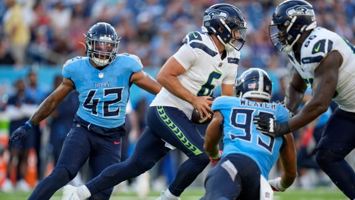 Seattle Seahawks quarterback Sam Howell (6) bolts between Tennessee Titans linebacker Caleb Murphy (42) and linebacker Rashad Weaver (99) during the first quarter at Nissan Stadium in Nashville, Tenn., Saturday, Aug. 17, 2024.