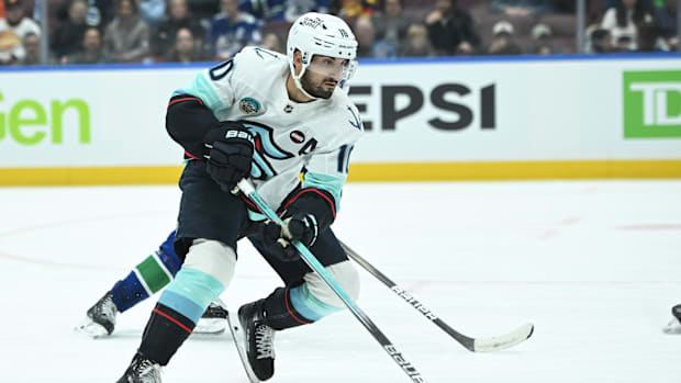 Hockey player in white uniform skates with the puc