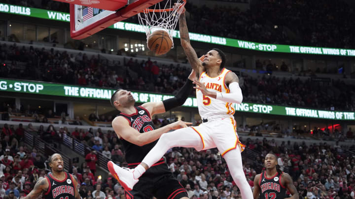 Apr 17, 2024; Chicago, Illinois, USA; Atlanta Hawks guard Dejounte Murray (5) dunks the ball on Chicago Bulls center Nikola Vucevic (9) during the second half during a play-in game of the 2024 NBA playoffs at United Center. Mandatory Credit: David Banks-USA TODAY Sports